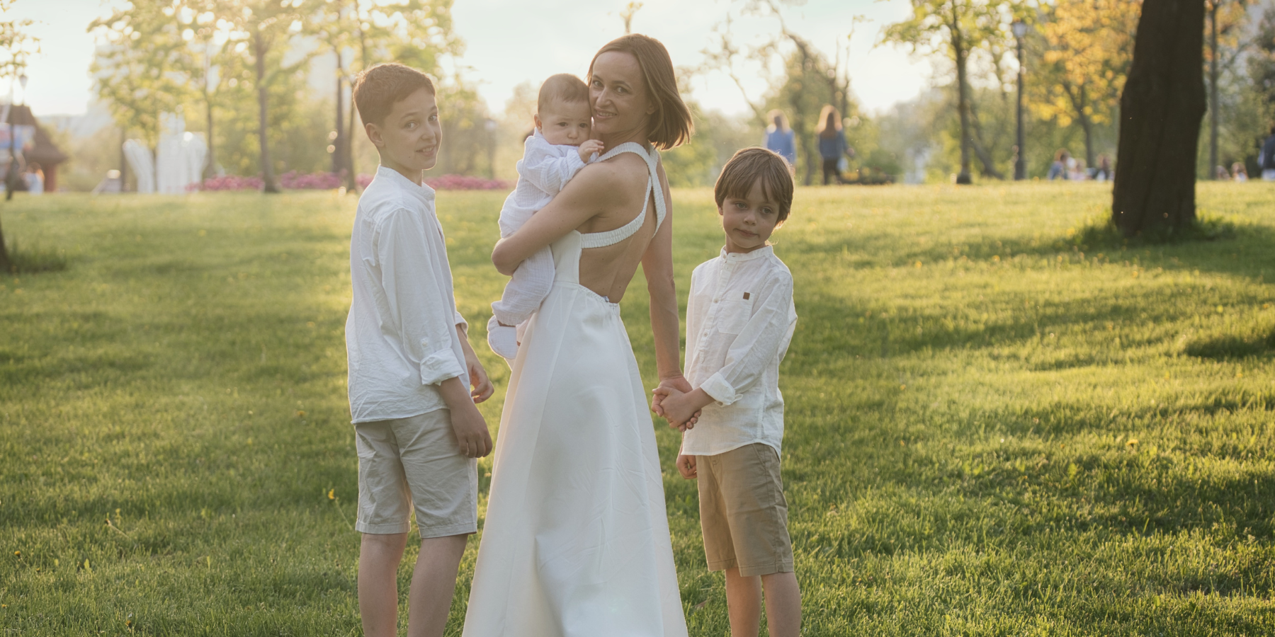 Mother in white dress with three boys from infant to pre-teen